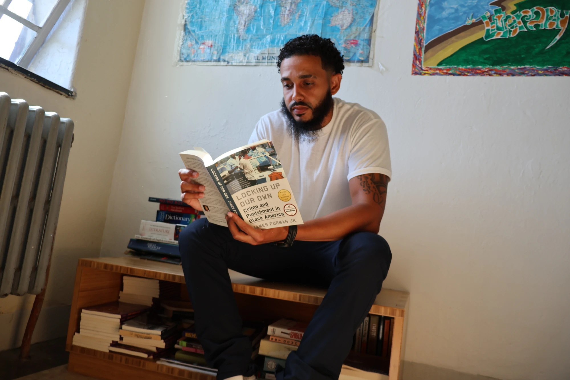 Freedom Library Patron Hector sits on a Freedom Library bench reading a book.