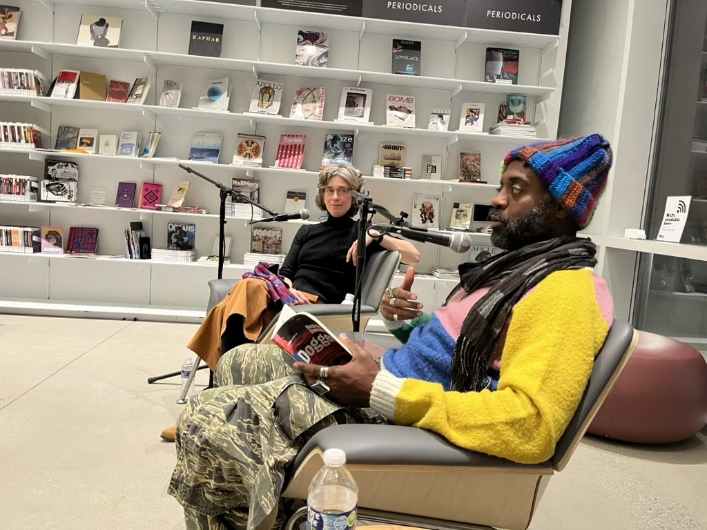 Two people sitting down with microphones