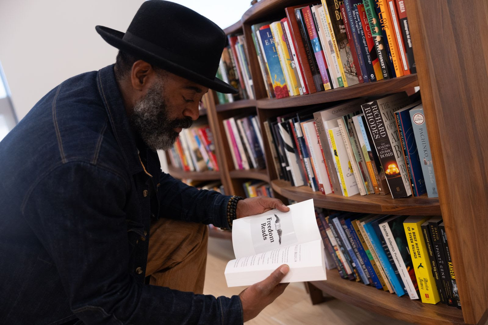 Freedom Reads Founder & CEO Reginald Dwayne Betts looks at book in Freedom Library