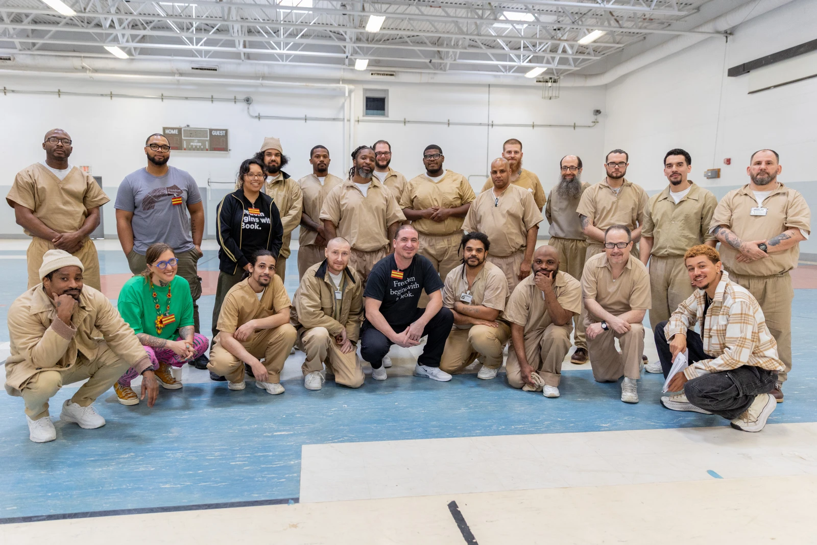Group photo with almost twenty men wearing khaki prison uniforms and the freedom reads team in black and gray t-shirts.