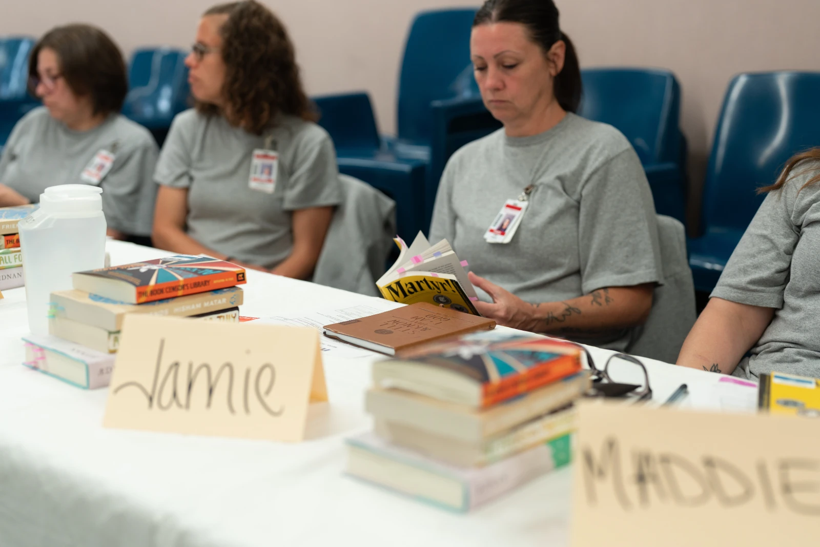 Women sitting at a table with stscks of books.