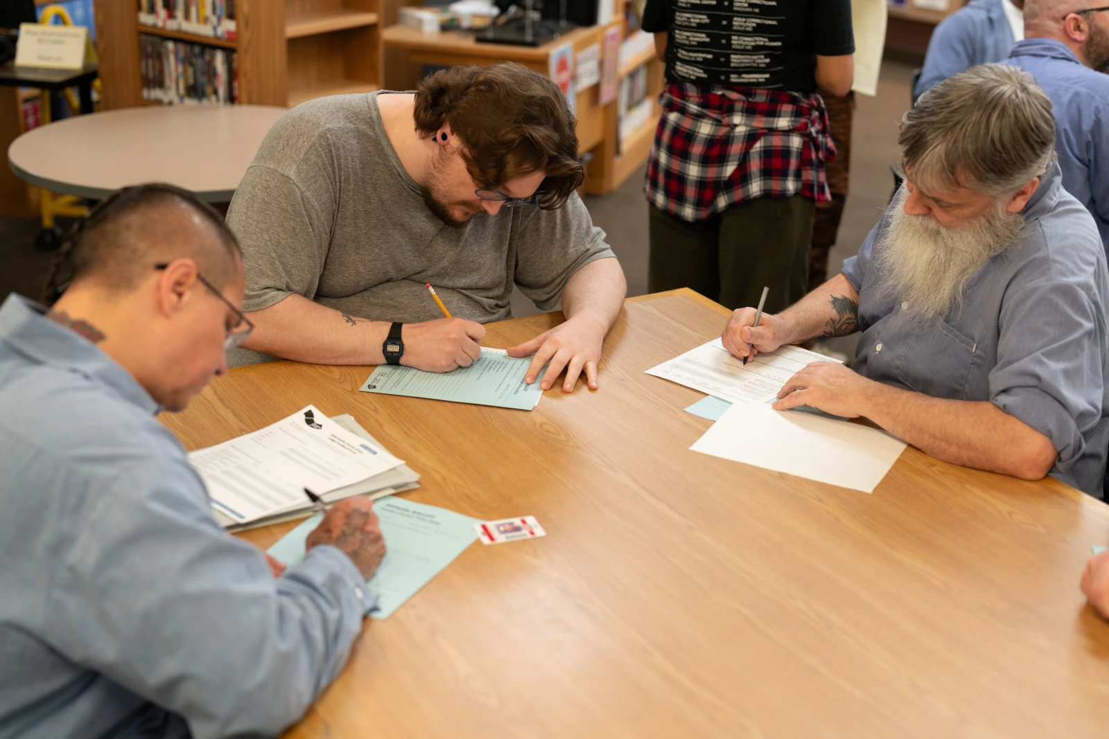 Men at a table filling out paper forms.